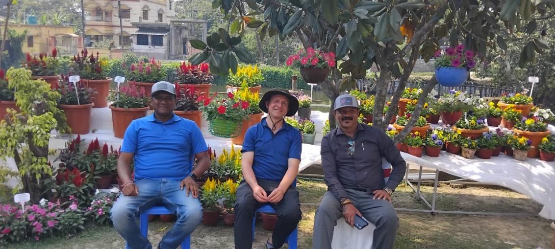 Animesh Ivan and Gautam sitting on a bench in front of the flowers display in preparation of Flowers Show Kolkata